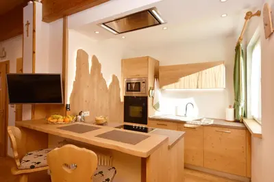 a kitchen with wooden cabinets and a counter top at Majon d'Aisciuda in Vigo di Fassa