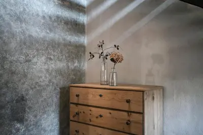 a wooden dresser with a vase of flowers on it at St. Vigilius modern historic apartments in Nalles