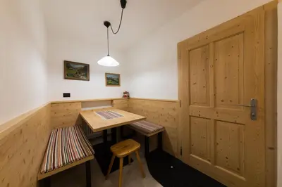 a room with a wooden door and a table and stool at Casa Sartori in Tesero