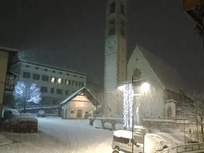 a church covered in snow with a christmas tree in front at Casa Sartori in Tesero