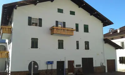 a white building with a wooden balcony on it at Casa Sartori in Tesero