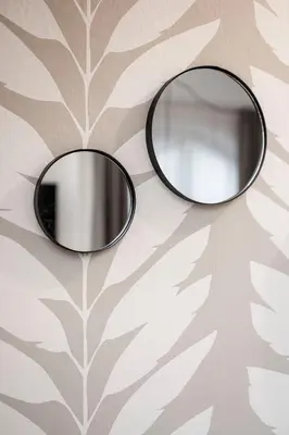 a mirror on a wall with a leaf wallpaper at Brixen City Maisonette in Bressanone