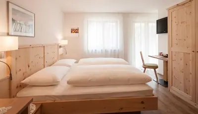 a bedroom with a large bed with white sheets at Garni Appartment Wagnerhof in Rablà