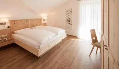 a bedroom with a bed and a chair and a window at Garni Appartment Wagnerhof in Rablà