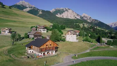 a house on a hill with mountains in the background at B&B Ciastel in San Vigilio Di Marebbe