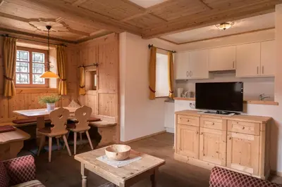 a kitchen and living room with a table and a tv at B&B Ciastel in San Vigilio Di Marebbe