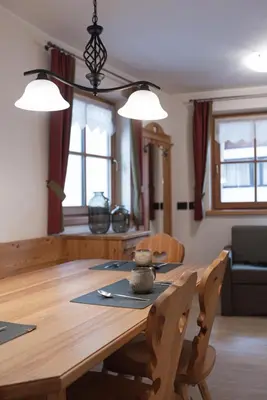 a dining room with a wooden table with two lights at Chalet Tyrolian Apartments - by Familiaris - Pools 500 meters in Valdaora