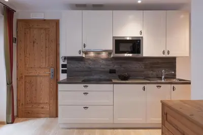 a kitchen with white cabinets and a microwave at Chalet Tyrolian Apartments - by Familiaris - Pools 500 meters in Valdaora