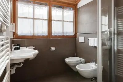 a bathroom with two sinks and a toilet and a window at Chalet Tyrolian Apartments - by Familiaris - Pools 500 meters in Valdaora