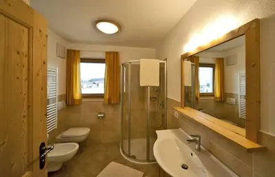 a bathroom with two toilets and a sink and a shower at Bartlmairhof in San Giorgio