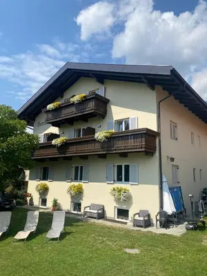 a large yellow building with chairs in a yard at Garni Hattlerhof B&B in Brunico