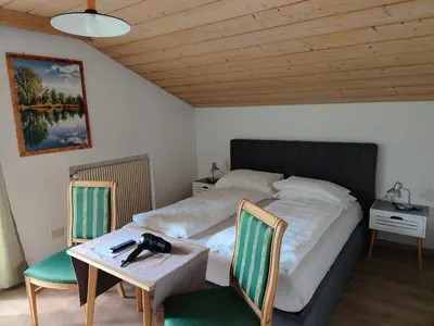 a bedroom with a bed with a table and two chairs at Garni Hattlerhof B&B in Brunico