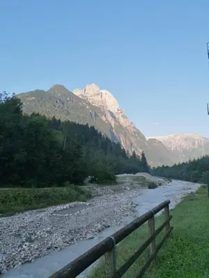 a river with a fence next to a mountain at Apartment Al Sasso in Taibon