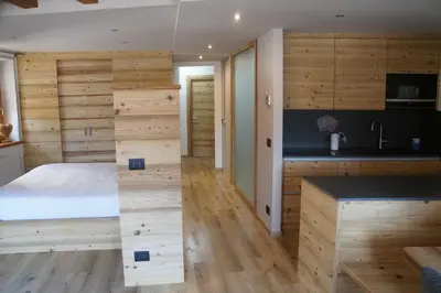 a bedroom with wooden walls and a bed and a kitchen at Apartment Al Sasso in Taibon