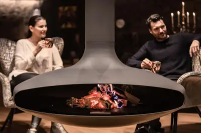 a man and woman sitting around a fire place at Boutique Hotel Kircher in Sarntal