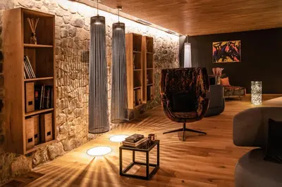 a living room with a stone wall and a chair at Boutique Hotel Kircher in Sarntal