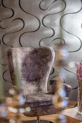a chair sitting in a room with a wall at Boutique Hotel Kircher in Sarntal