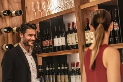 a man standing in front of a shelf of wine bottles at Boutique Hotel Kircher in Sarntal