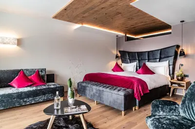 a bedroom with a bed and two couches at Boutique Hotel Kircher in Sarntal