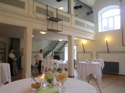 a dining room with white tables and people standing in the background at Residence Zum Theater in Colle Isarco
