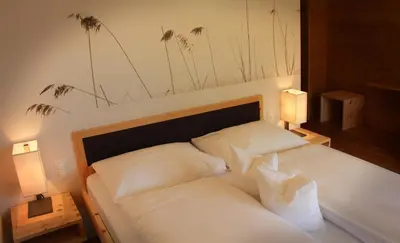 a bedroom with a bed with white sheets and two lamps at Steindl's Boutique Hotel in Vipiteno