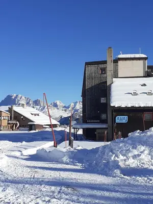 a snow covered street with a building in the background at Casa Neve e Sole - presso Sussy Residence in Falcade