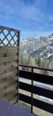 a view of the mountains from a wooden fence at Casa Neve e Sole - presso Sussy Residence in Falcade