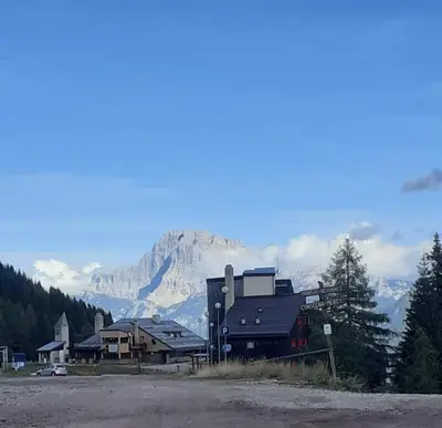 a large building with a mountain in the background at Casa Neve e Sole - presso Sussy Residence in Falcade