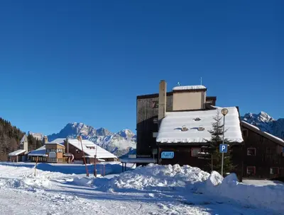 a building covered in snow in front of a mountain at Casa Neve e Sole - presso Sussy Residence in Falcade