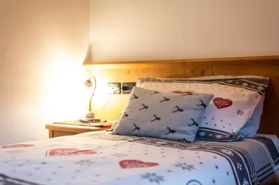 a bedroom with a bed with pillows and a lamp at Mansarda Cermis in Cavalese