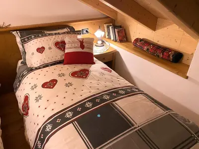 a small bedroom with a bed with hearts and snow at Mansarda Cermis in Cavalese