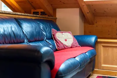 a blue leather couch with a red pillow on it at Mansarda Cermis in Cavalese