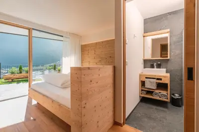 a small bedroom with a bed and a large window at Innermoser Bauernhof - Chalets in Molini di Tures