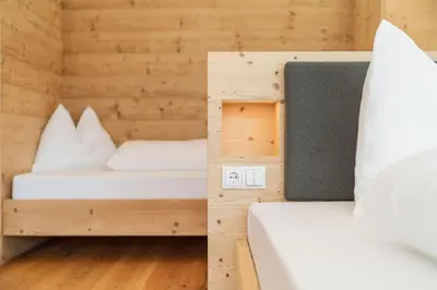 two beds in a room with wooden walls at Innermoser Bauernhof - Chalets in Molini di Tures