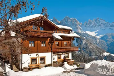 a building in the snow with mountains in the background at Chalet in Funes Valley with Dolomites Views in Funes