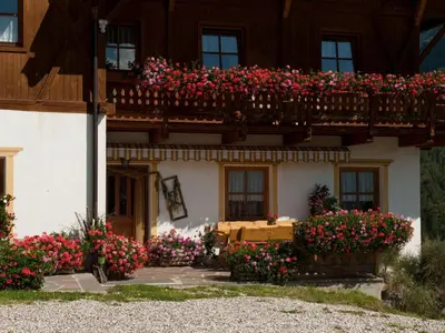a house with flowers on a balcony at Chalet in Funes Valley with Dolomites Views in Funes