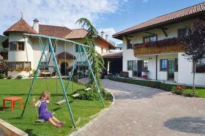 a little girl playing on a swing in front of a house at Apartment in Brixen with Pool & Dolomites Views in Naz-Sciaves