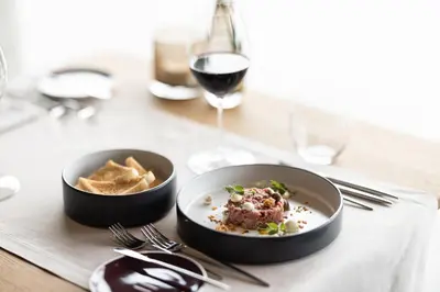 a table with a plate of food and a glass of wine at Santre dolomythic home in Bressanone