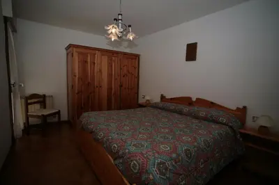 a bedroom with a bed and a chandelier at Appartamenti Cercenà in Canazei