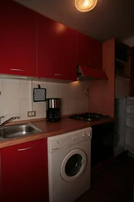 a kitchen with red cabinets and a washing machine at Appartamenti Cercenà in Canazei