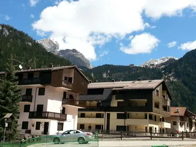 a apartment building with a car parked in front of it at Appartamenti Cercenà in Canazei
