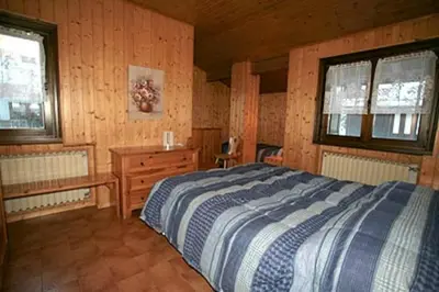 a bedroom with a bed and a wooden wall at Appartamenti Cercenà in Canazei