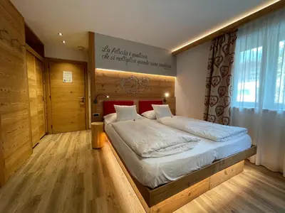 a bedroom with a large bed with a wooden headboard at B&B Cèsa Planber Mountain View SKI-IN SKI-OUT in Canazei