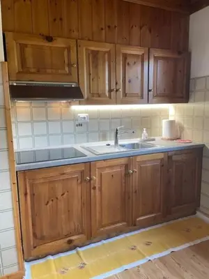 a kitchen with wooden cabinets and a sink at Chalet Scoiattolo Residence Sussy in Falcade