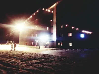 two people standing in front of a building at night at Chalet Scoiattolo Residence Sussy in Falcade
