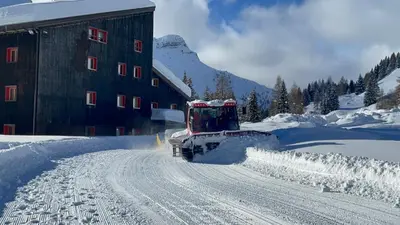 a snow truck driving down a snow covered road at Chalet Scoiattolo Residence Sussy in Falcade