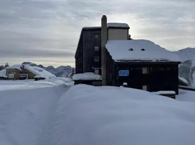 a building covered in snow next to a pile of snow at Chalet Scoiattolo Residence Sussy in Falcade