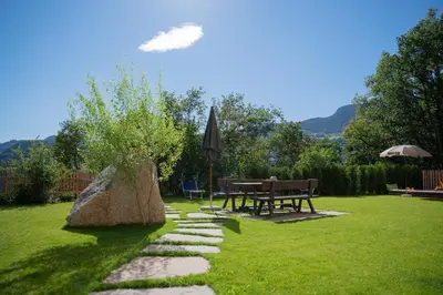 a garden with a table and an umbrella and grass at Fortschöllhof in Castelrotto