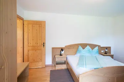 a bedroom with a wooden bed with blue pillows at Fortschöllhof in Castelrotto