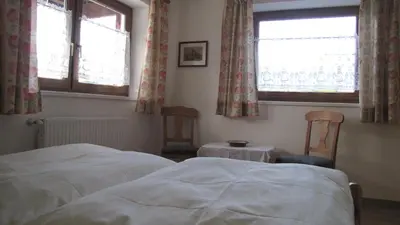 a bedroom with two beds and two chairs and two windows at Blasbichler Appartments in Brunico